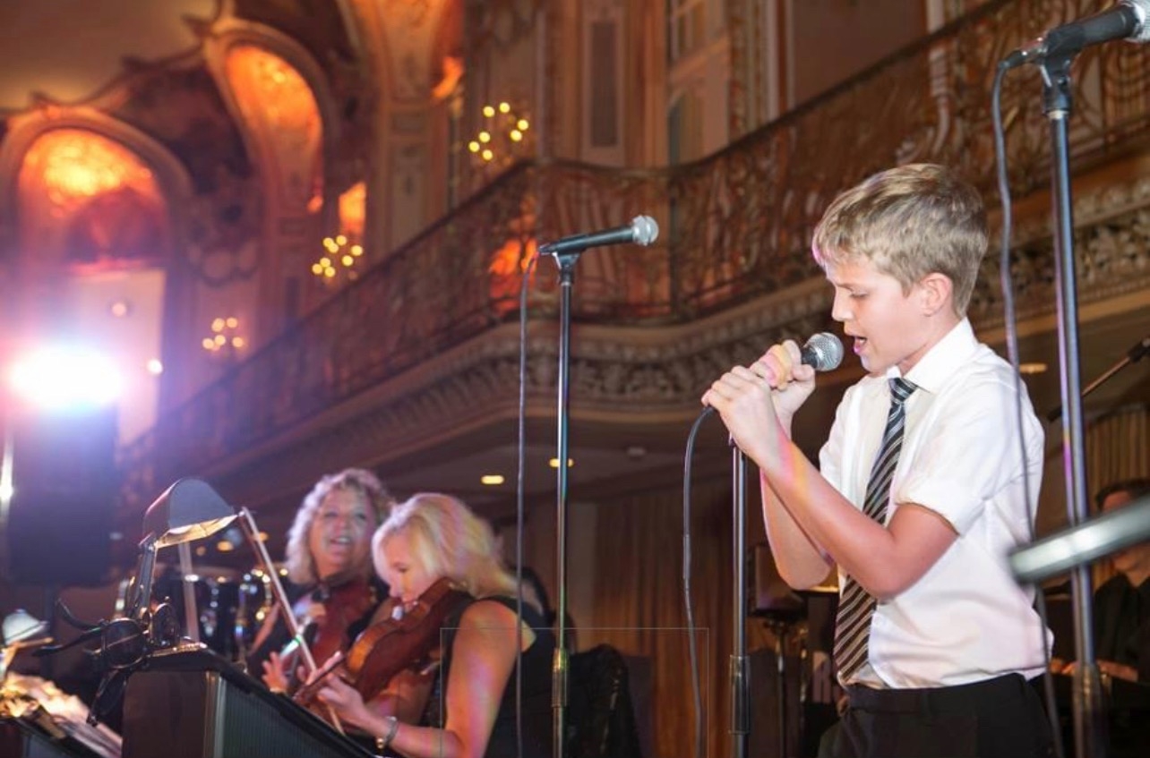 A young Michael Patrick Joyce singing on stage at an early performance