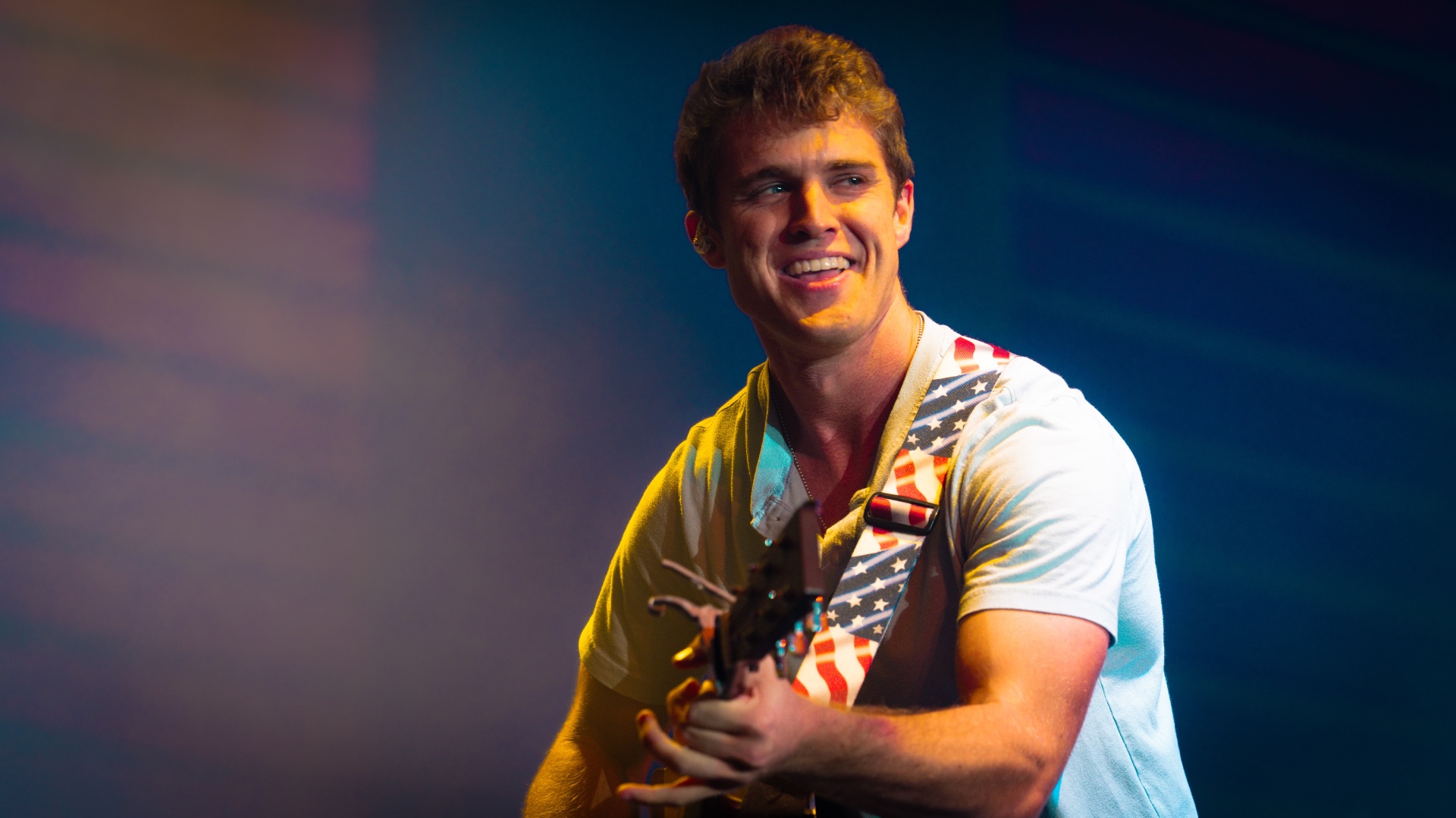 Michael Patrick Joyce smiling on stage with an American flag guitar strap